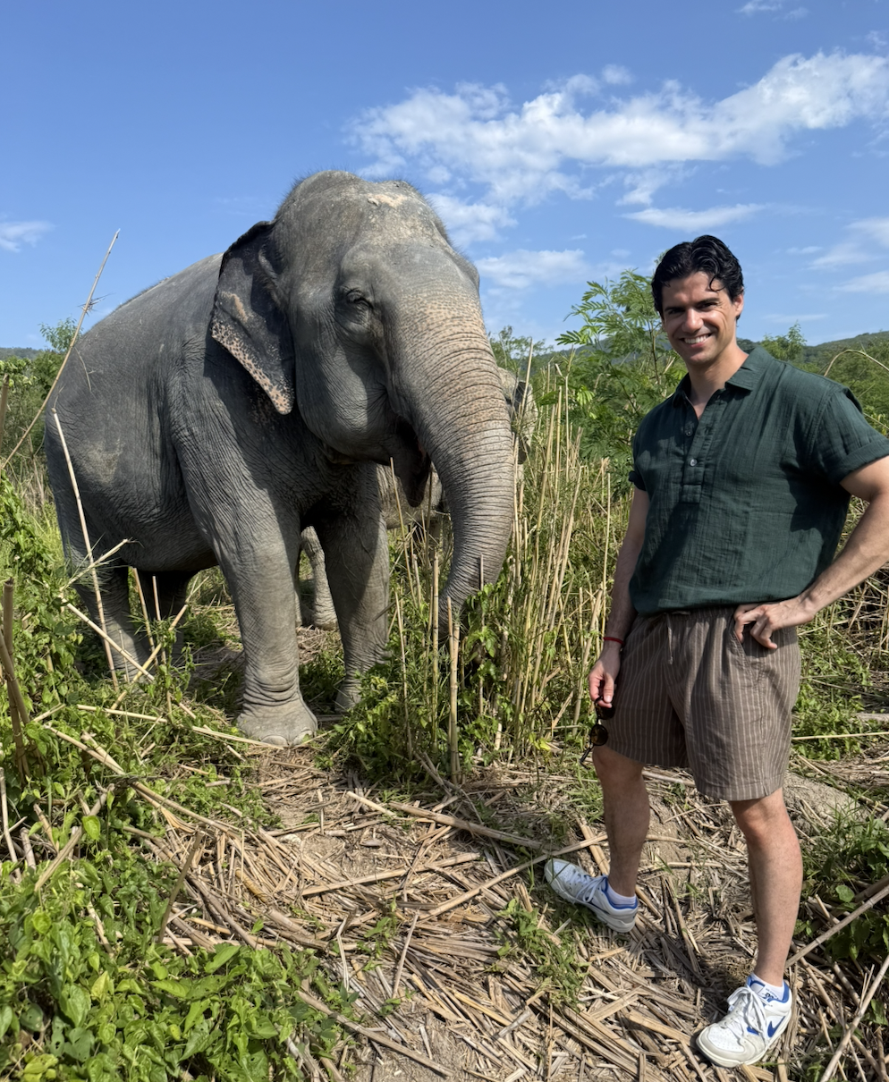 Nicolas Diez standing next to an elephant in a green field